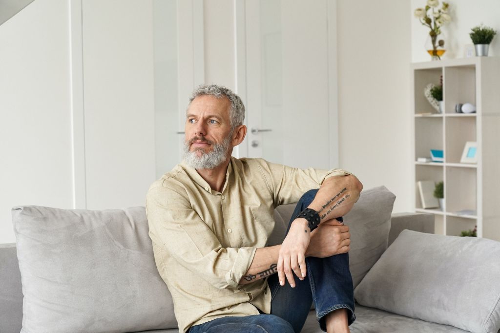Relaxed mature thoughtful man relaxing sitting on sofa and thinking at home.